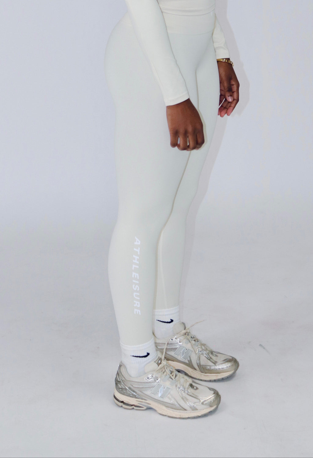 Person wearing a white long-sleeve top and leggings set on a plain background