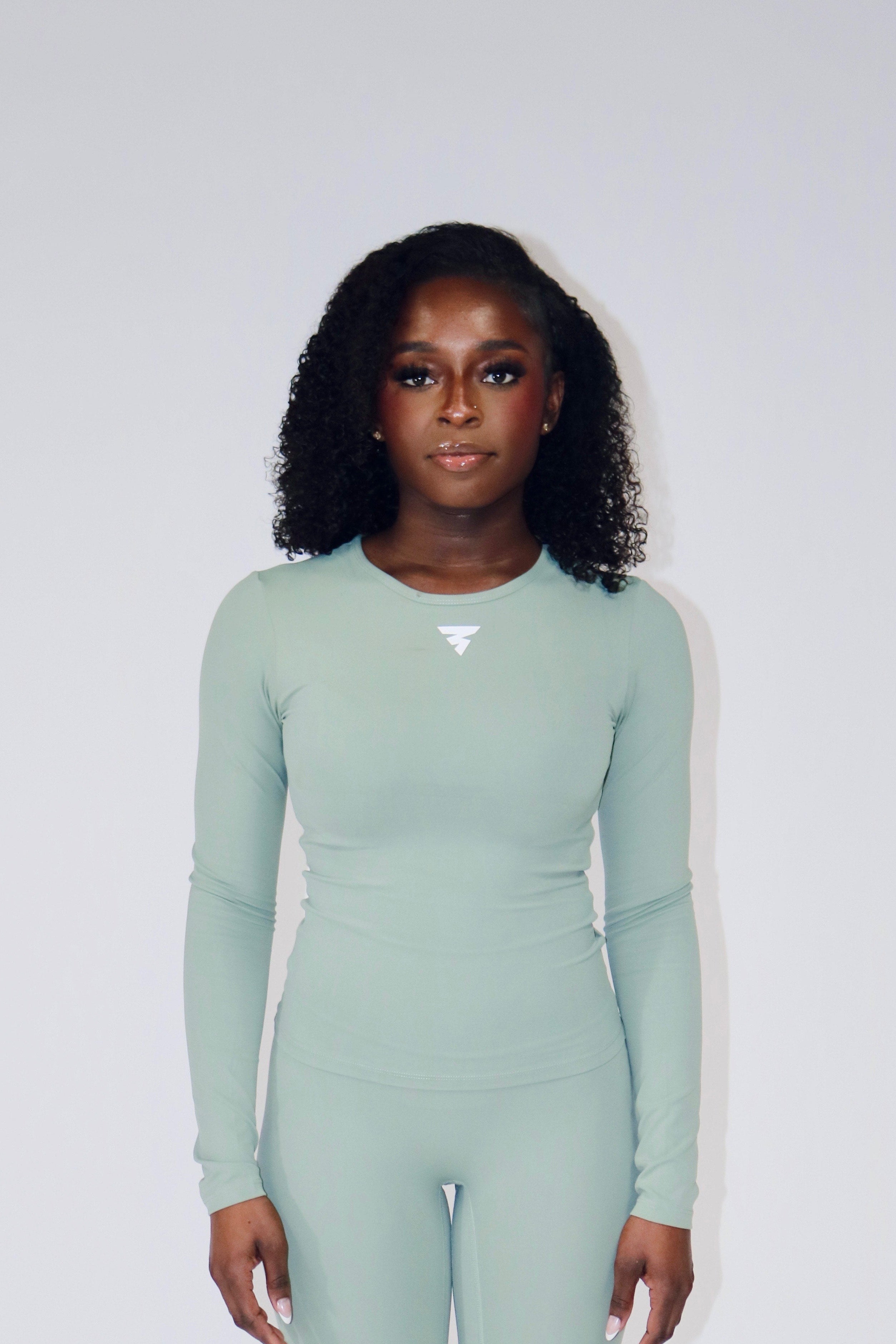 Person wearing a light green yoga set on a white background