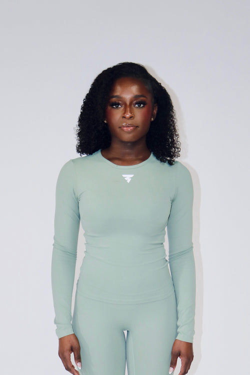 Person wearing a light green yoga set on a white background